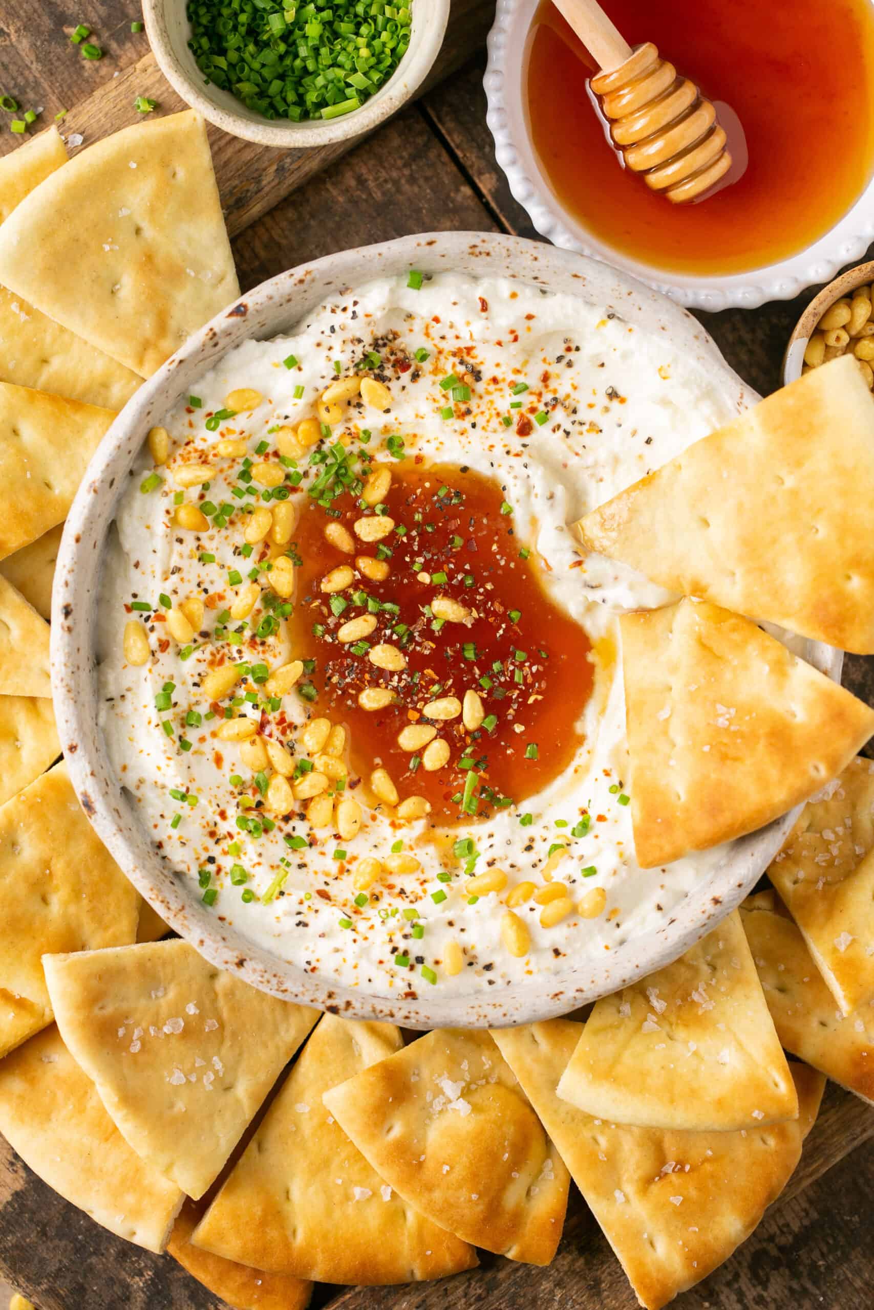 Whipped feta with honey in a bowl with pita chip on the side.