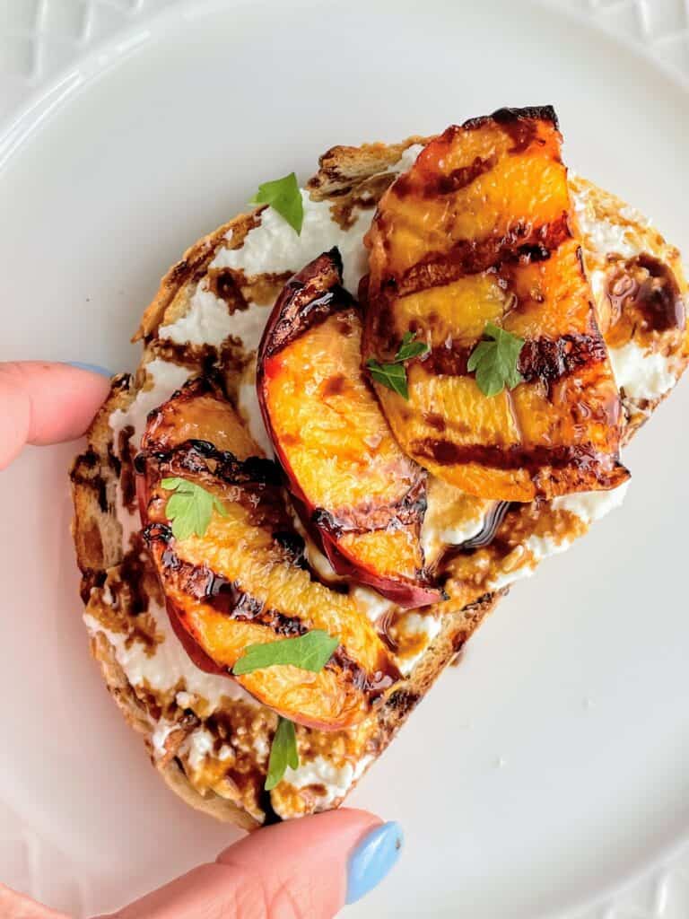 Grilled Peaches, Balsamic Glaze, and Whipped Feta on toast on a plate.