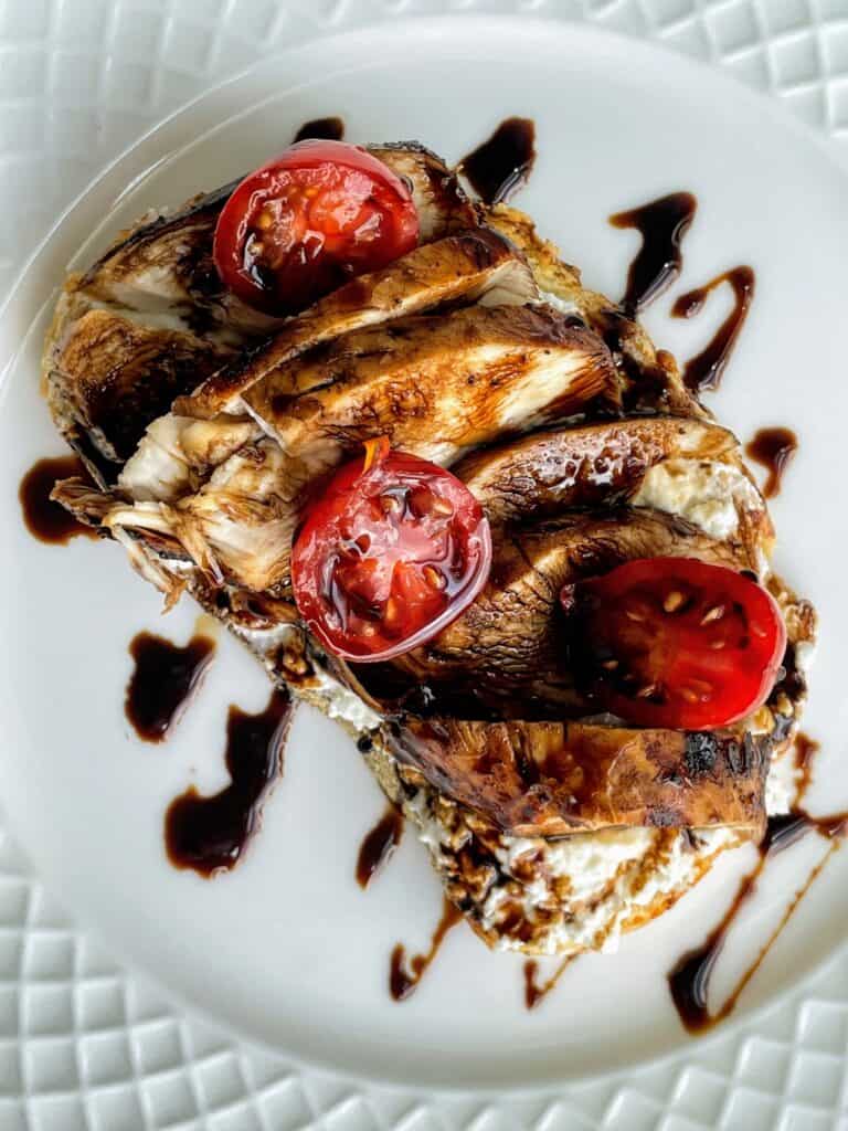 Grilled Chicken, Sliced Tomatoes, Balsamic Glaze, and Whipped Feta on toast on a plate.