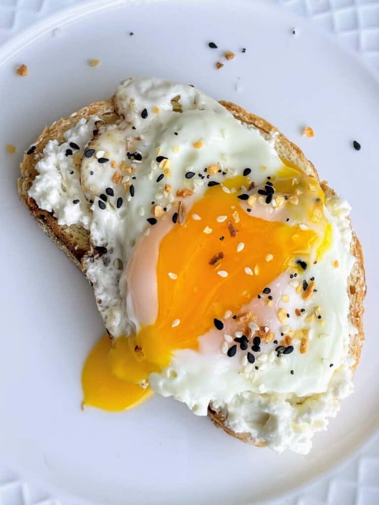 Over Easy Egg, Everything But The Bagel Seasoning, and Whipped Feta on toast on a plate.