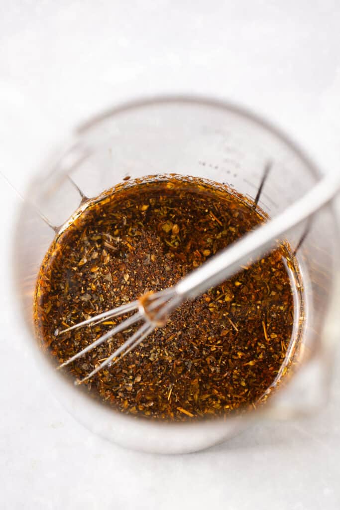 Spices in a small bowl with a whisk.