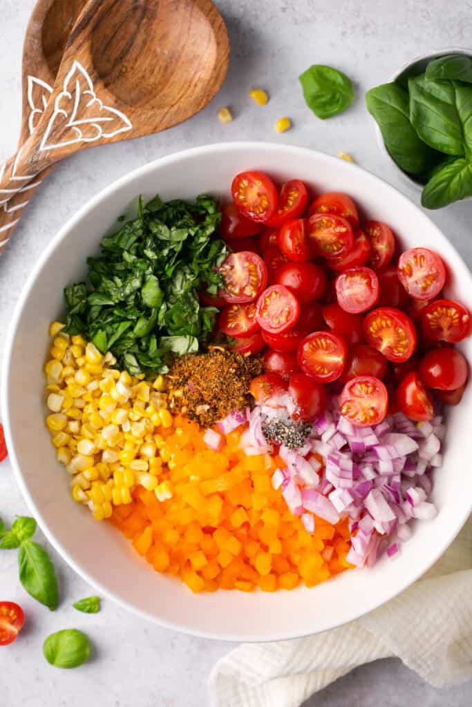 Ingredients for rainbow corn salad in a bowl before being mixed together.