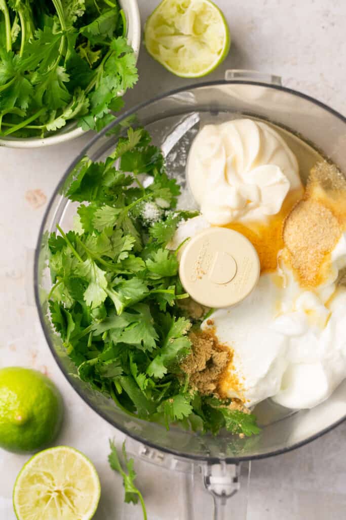 Ingredients for cilantro lime crema in a food processor bowl before being processed.