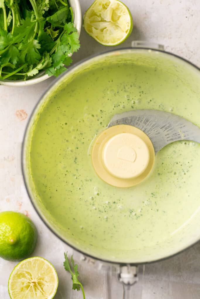 Ingredients for cilantro lime crema in a food processor bowl after being processed.