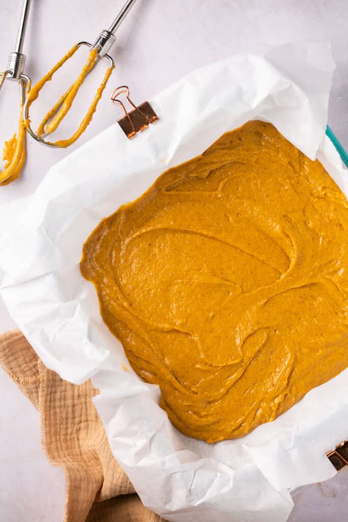 Healthy pumpkin coffee cake batter in a square baking dish with parchment paper.