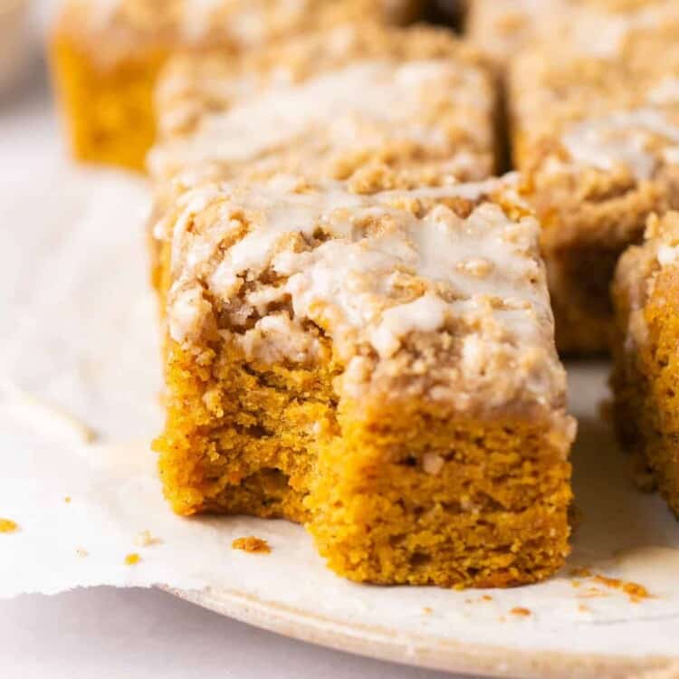 Zoomed in view of a square of healthy pumpkin coffee cake topped with glaze on a plate.