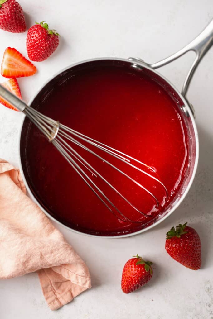 Strawberry mixture ingredients in a saucepan with a whisk.