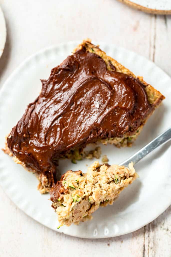 Zoomed in view of baked zucchini oatmeal with nutella spread on a small plate with a fork.