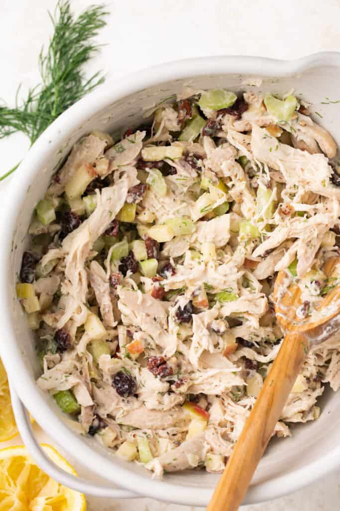 Easy apple pecan chicken salad recipe served in a bowl with a wooden spoon.