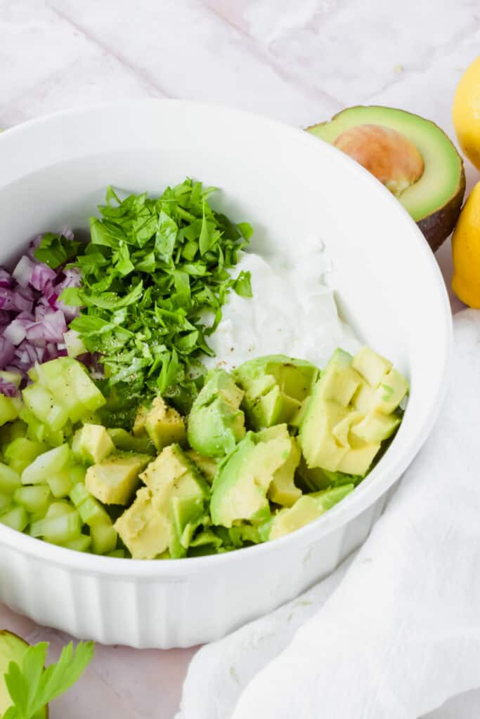 Ingredients for avocado greek yogurt chicken salad in a bowl before being mixed up.