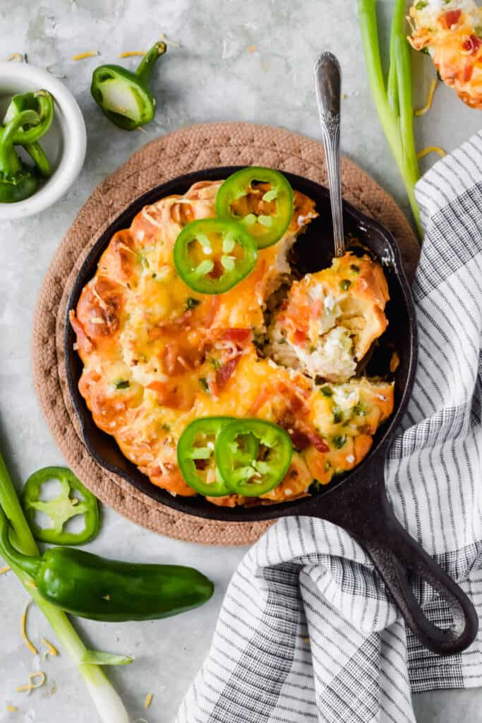 Jalapeno popper chicken dip in a skillet with a spoon.