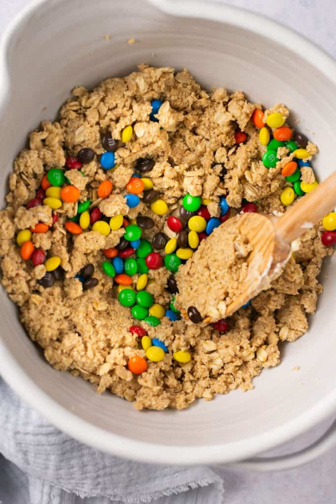 M&Ms foled into the monster protein cookie dough bars mixture in a mixing bowl.