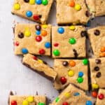 Monster protein cookie dough bars cut into squares on parchment paper.