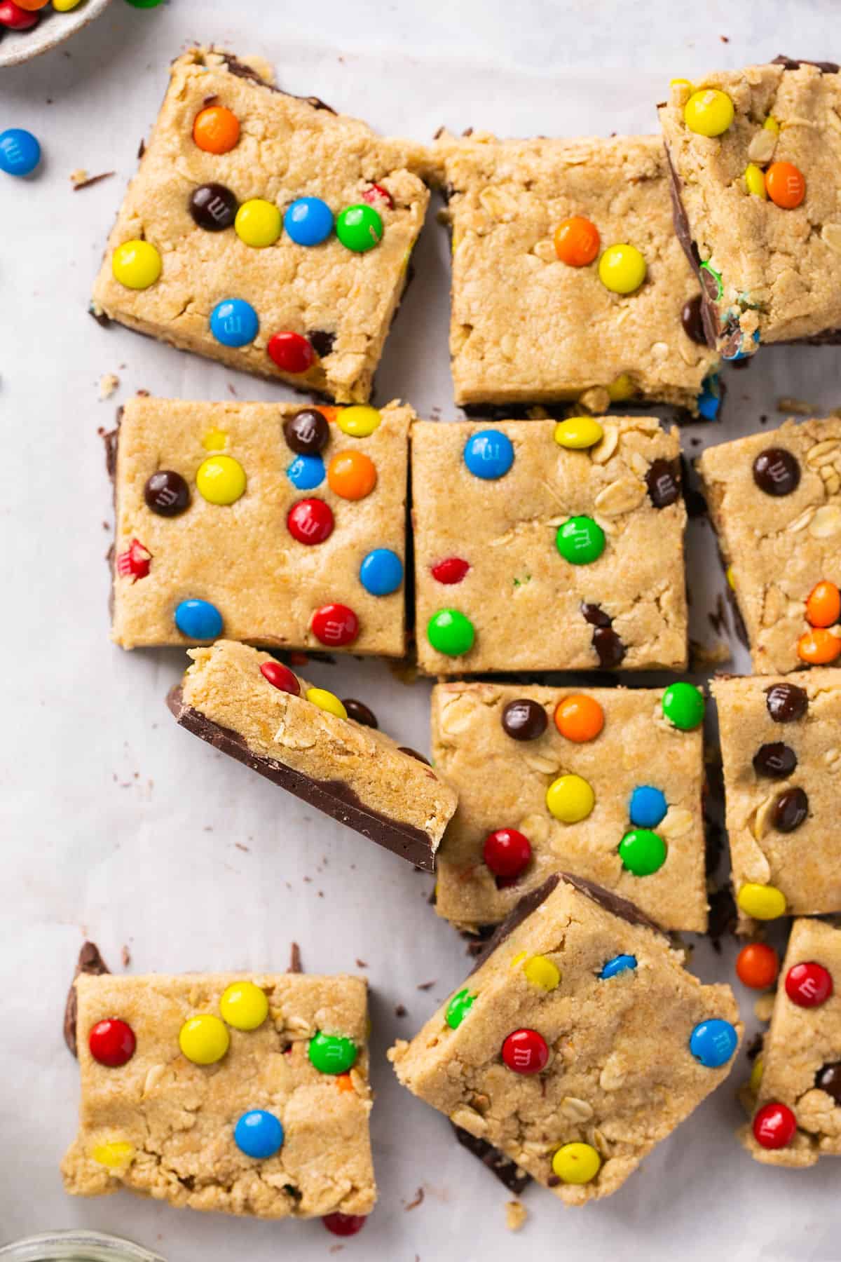 Monster protein cookie dough bars cut into squares on parchment paper.