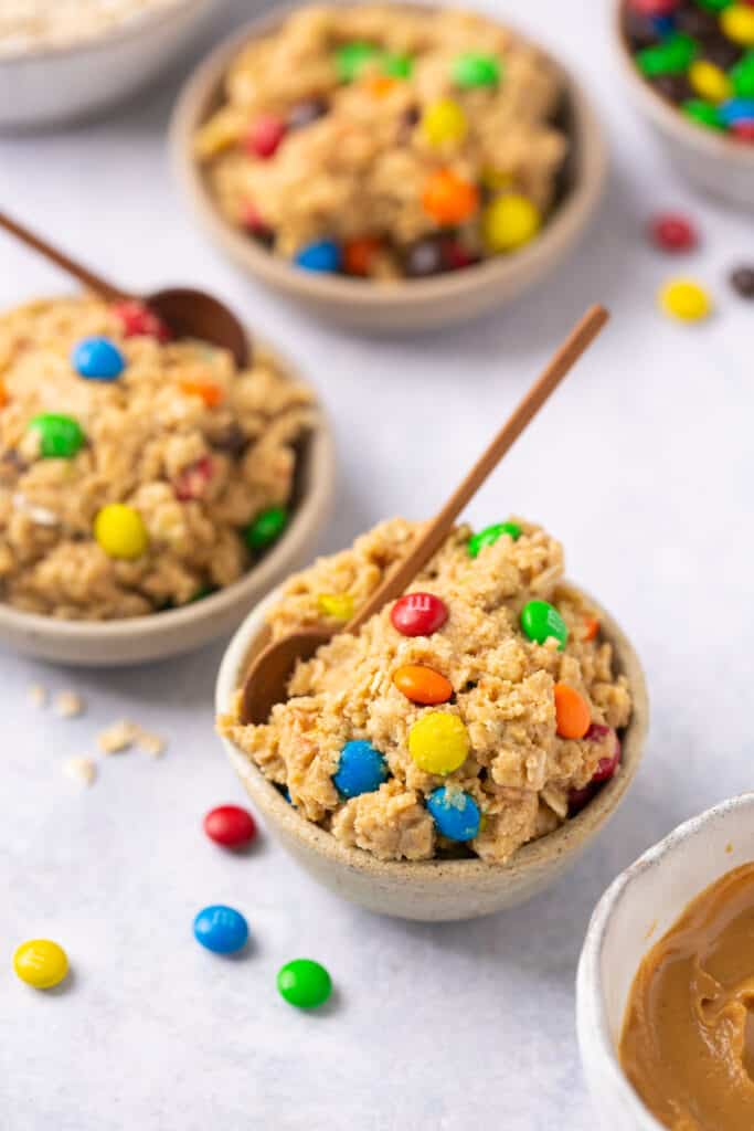 Monster protein cookie dough with colorful M&Ms served in a small bowl with a spoon
