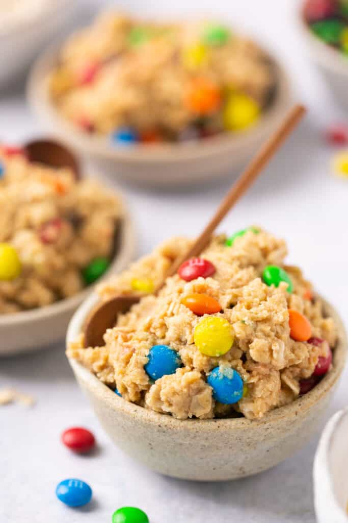 Monster protein cookie dough with colorful M&Ms served in a small bowl with a spoon
