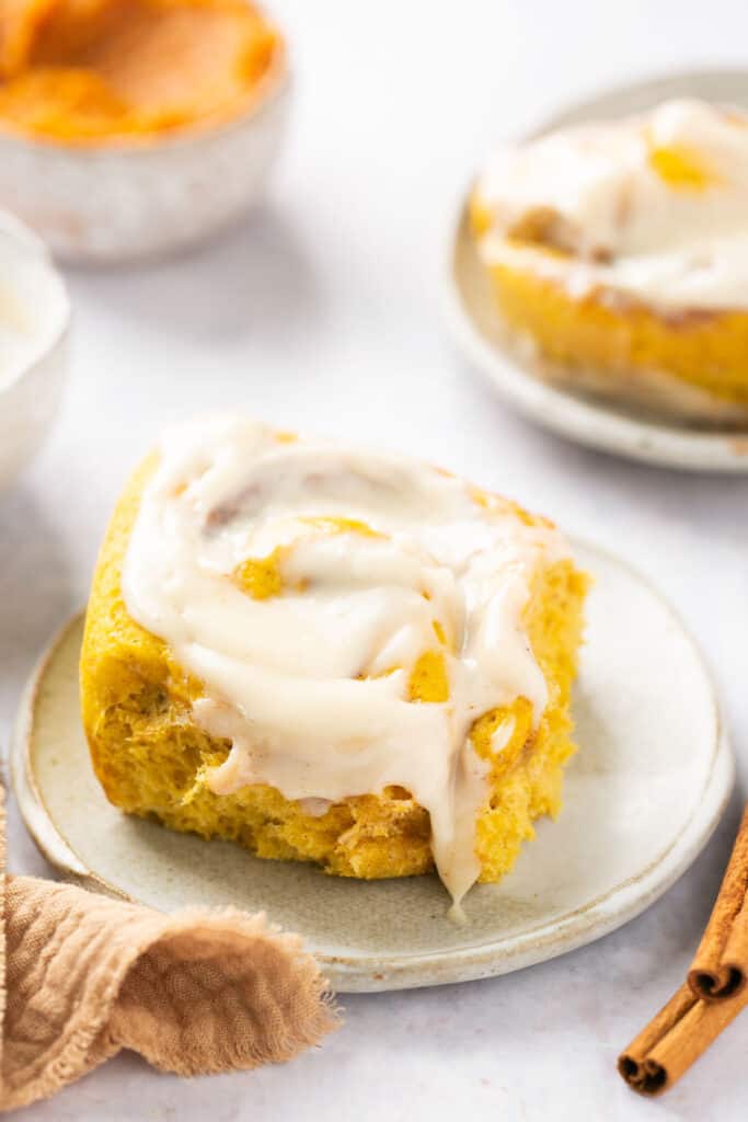Healthy pumpkin cinnamon roll with cream cheese icing served on a small plate