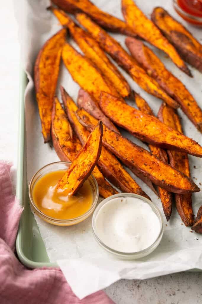 Simple seasoned air fryer sweet potato wedges on a tray with dipping sauces
