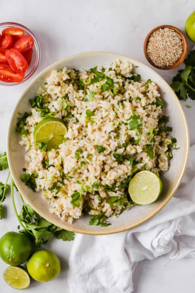 Chipotle brown rice recipe in a bowl garnished with cilantro and lime.