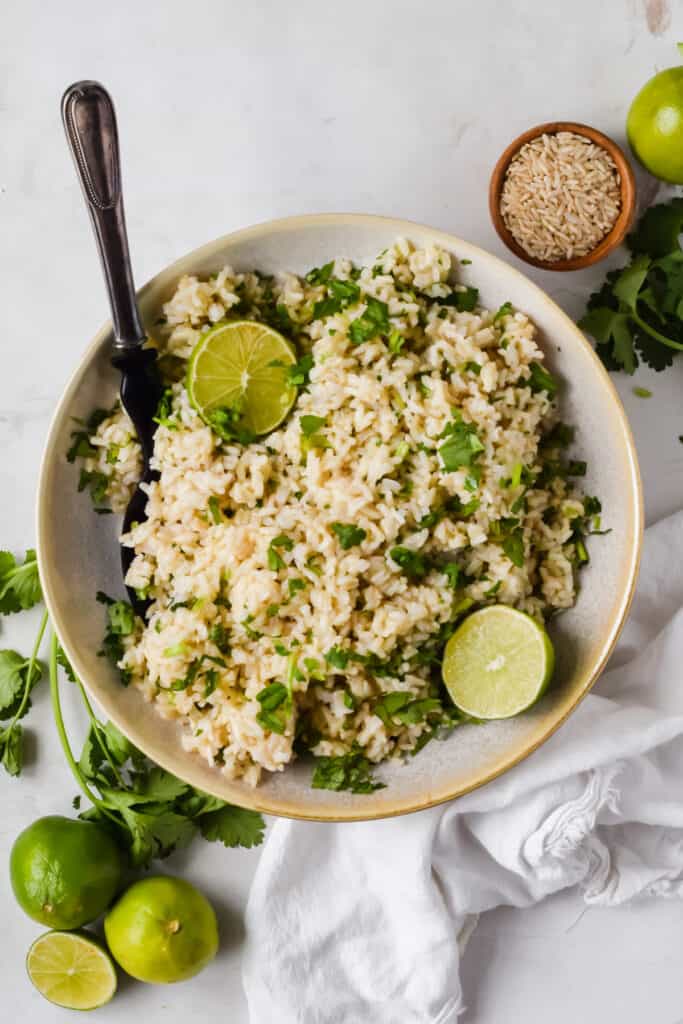 Chipotle brown rice recipe in a bowl with a fork garnished with cilantro and lime.