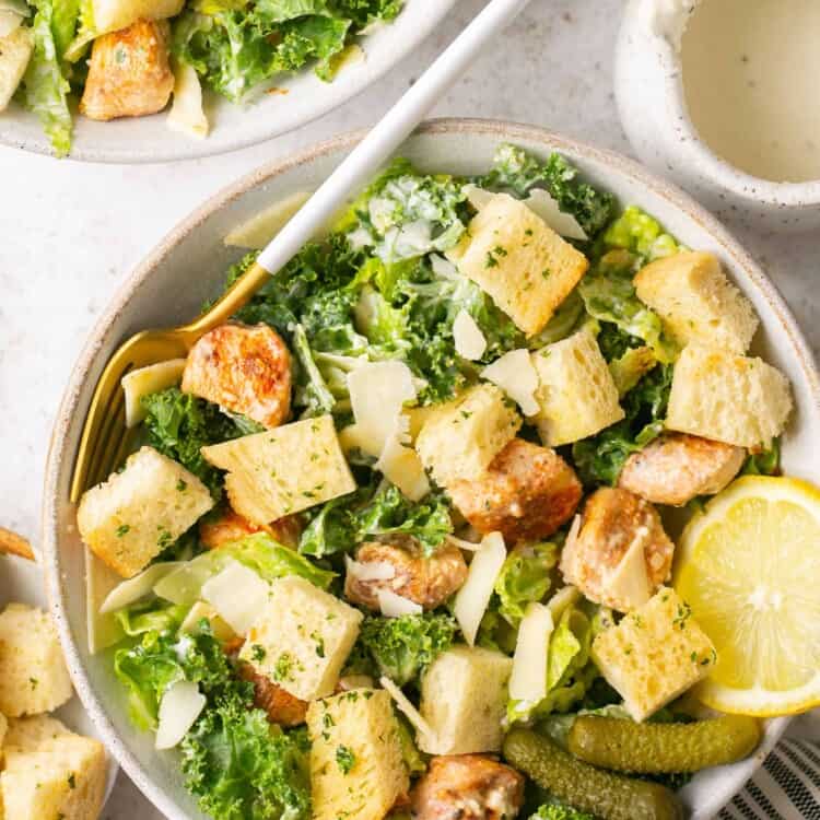 Healthy chicken caesar salad topped with croutons in a bowl with a fork.