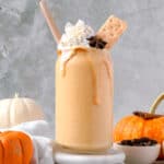 Pumpkin protein shake recipe served in a jar with a straw topped with whipped cream.