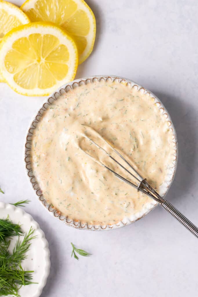 Lemon dill sauce in a small bowl with a whisk.