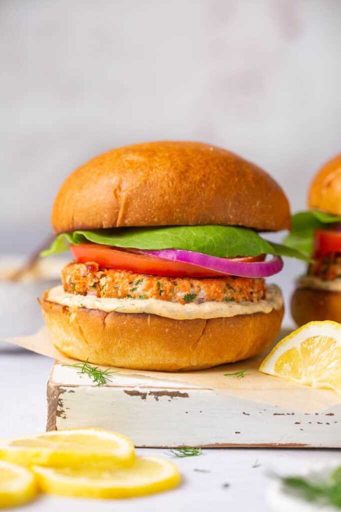 healthy salmon burger with veggie toppings and creamy lemon dill sauce on a bun