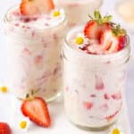 Strawberry overnight oats in a mason jar and sliced strawberries in and around jars.