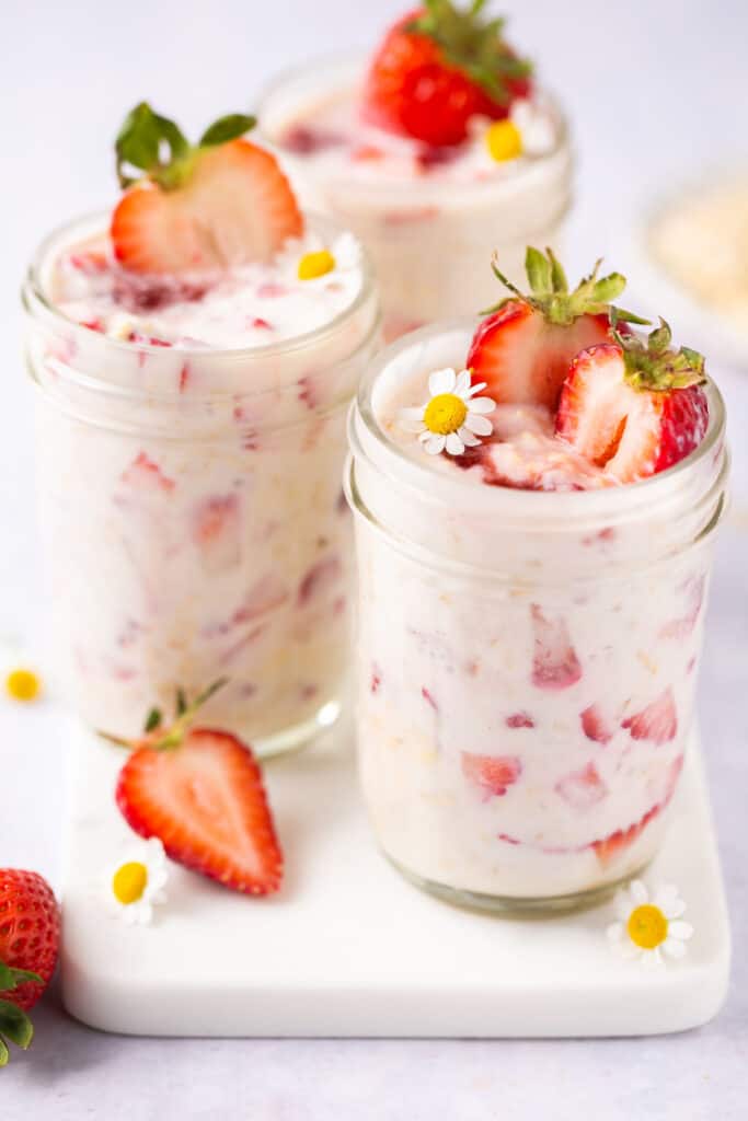 strawberry overnight oats in a mason jar and sliced strawberries in and around jars.