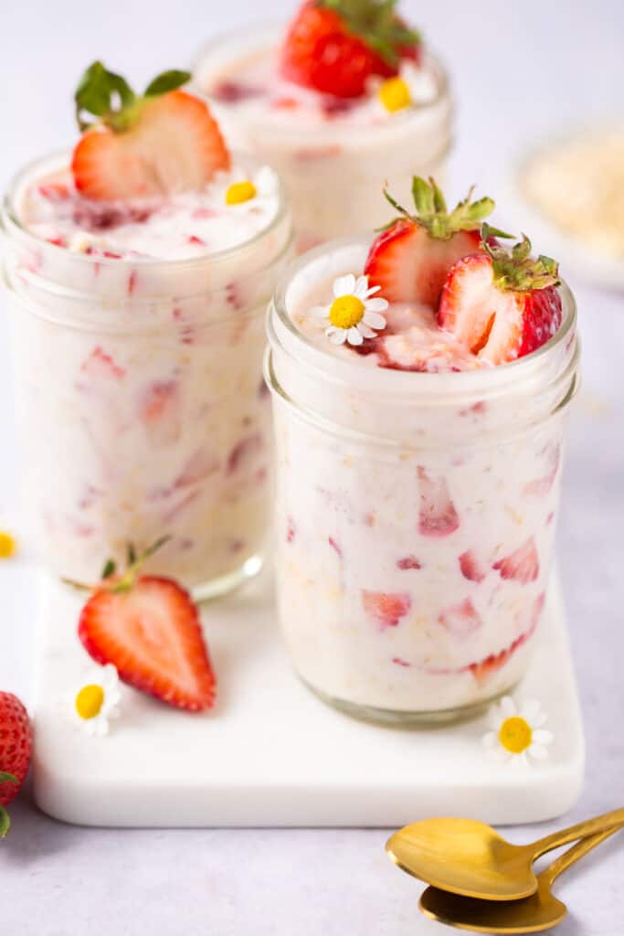 Strawberry protein overnight oats in jars topped with strawberry slices.