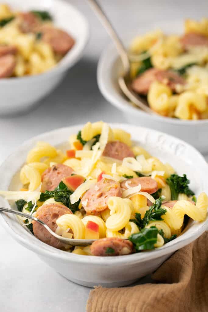 Sweet Apple Chicken & Gouda Skillet Pasta in a bowl with a fork topped with cheese