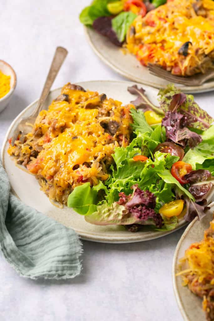 Cheeseburger spaghetti squash casserole served on a plate with a side salad