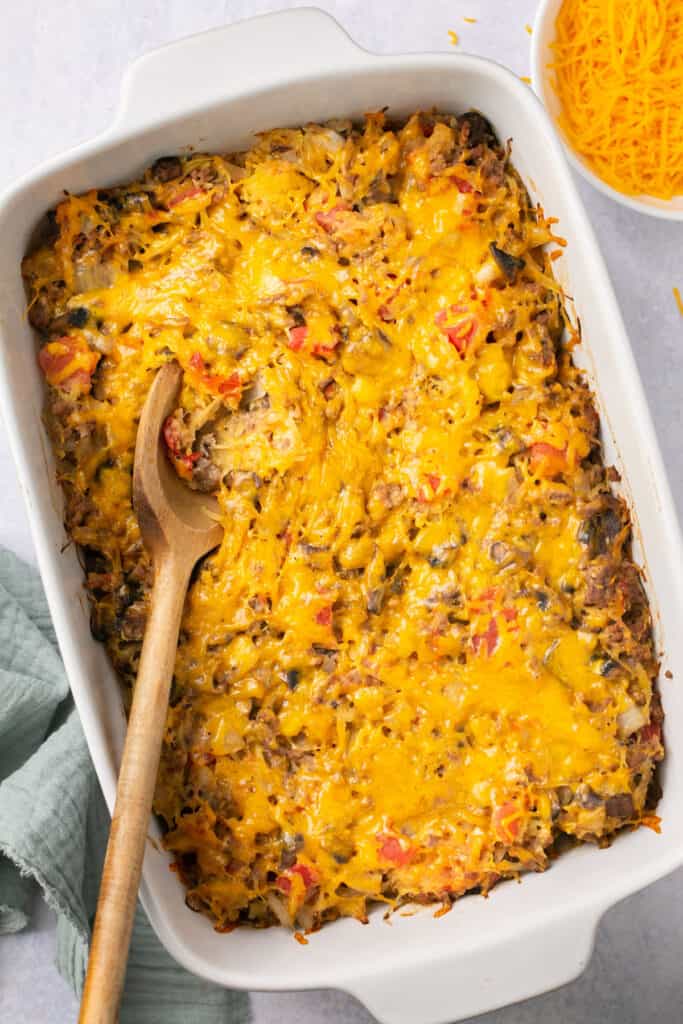 Cheeseburger spaghetti squash casserole in a baking dish with a wooden spoon after being baked