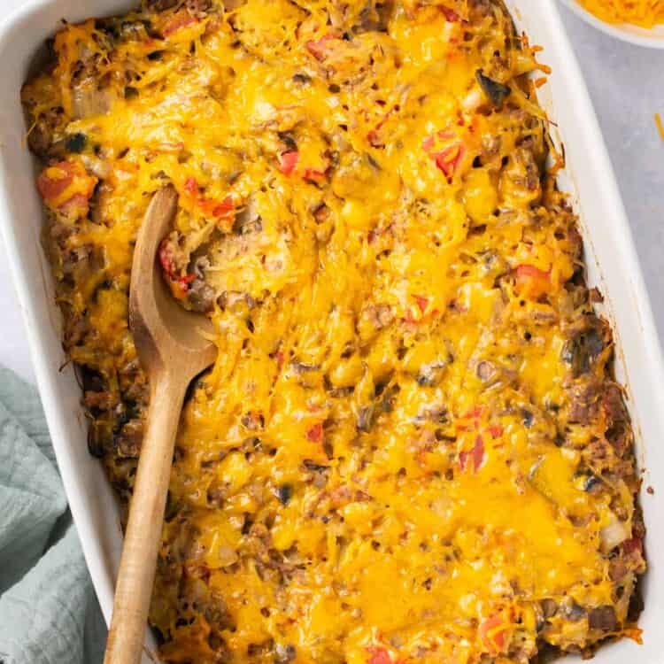 Cheeseburger spaghetti squash casserole in a baking dish with a wooden spoon.