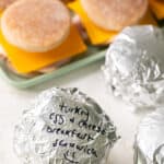 Meal prep breakfast sandwiches some on a tray and some wrapped with foil.