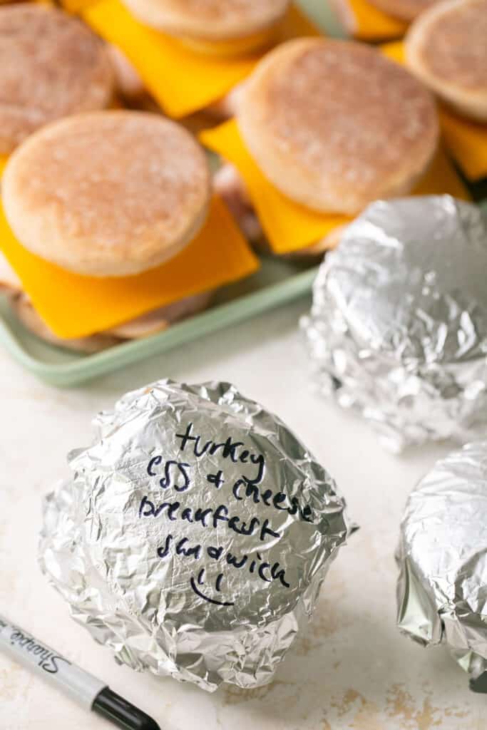 Meal prep breakfast sandwiches some on a tray and some wrapped with foil.