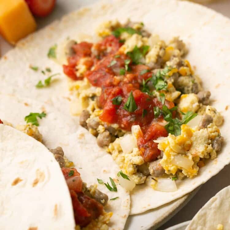 High protein breakfast tacos open faced on a plate with fruit.