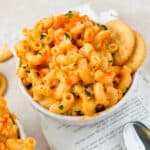 Buffalo chicken mac and cheese with cauliflower in small bowl garnished with Ritz crackers.