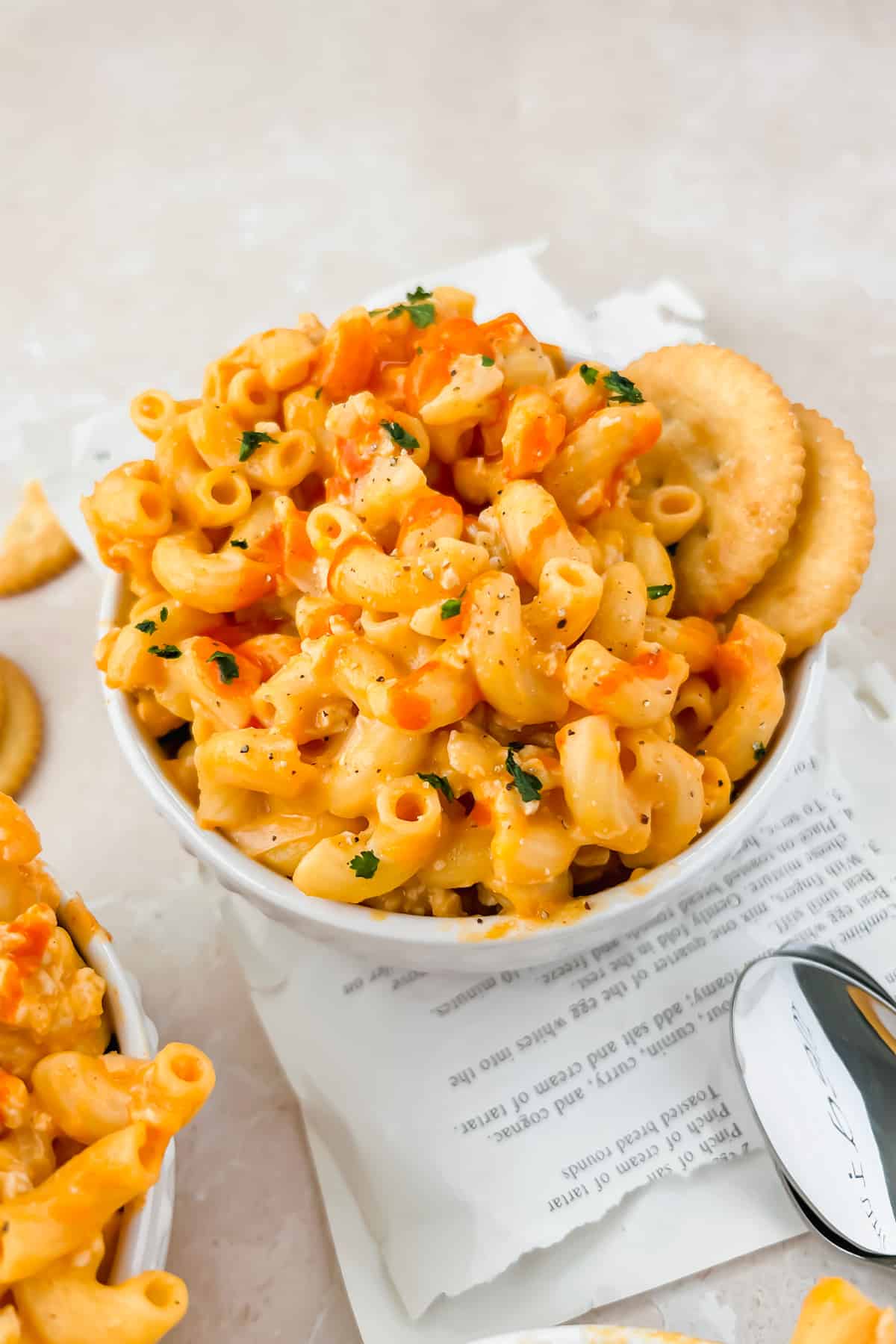Buffalo chicken mac and cheese with cauliflower in small bowl garnished with Ritz crackers.