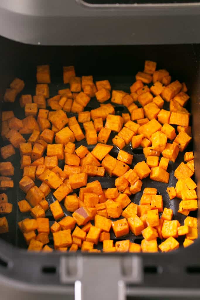 Cubed sweet potatoes in an air fryer basket after being cooked 