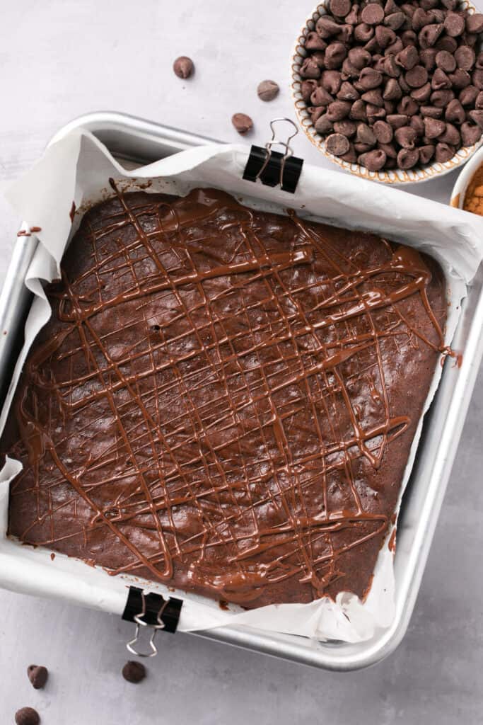 Chocolate drizzled over the healthy pumpkin brownies in a square baking pan.