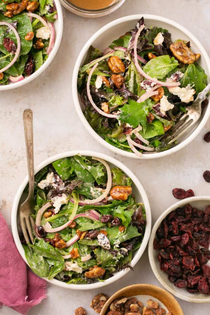 Simple salad with goat cheese and cranberries served in small bowls with forks