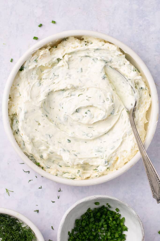 Herbed cream cheese in a small bowl with a spoon.