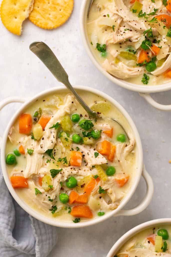 Macro Friendly Chicken Pot Pie Soup served in a bowl with a spoon topped with black pepper