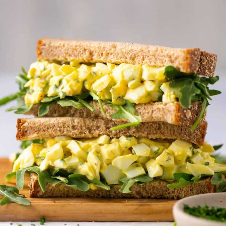Low calorie egg salad on a sandwich with greens, cut in halves and stacked vertically.