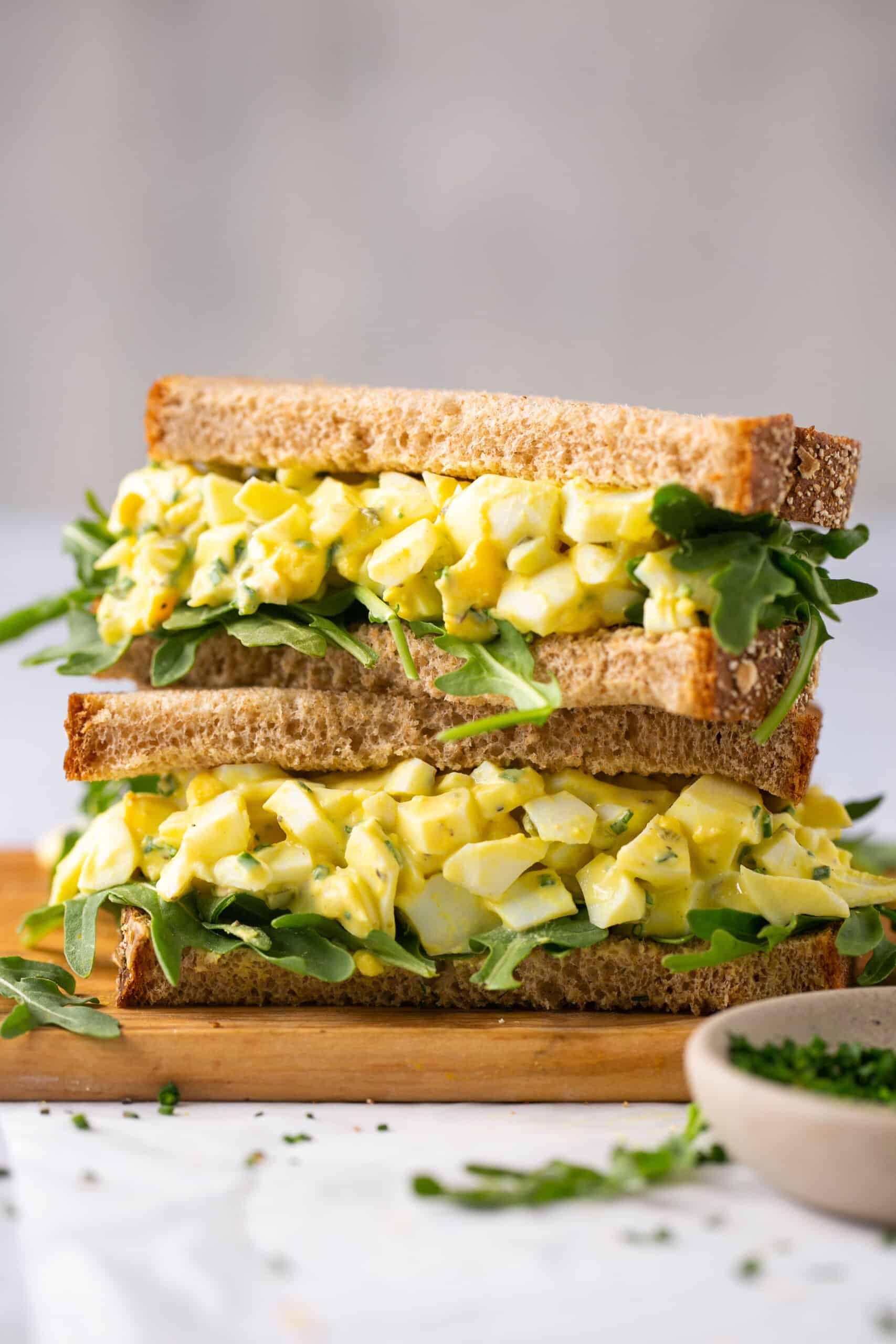 Low calorie egg salad on a sandwich with greens, cut in halves and stacked vertically.