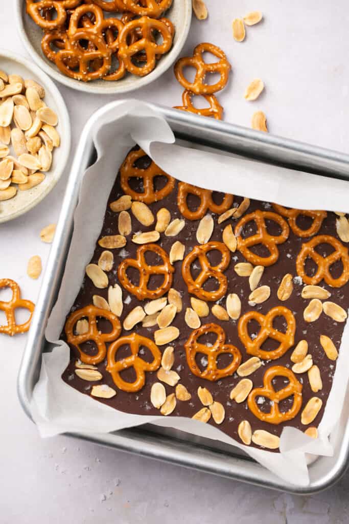 Dark chocolate pretzel bark in a square baking dish lined with parchment paper.