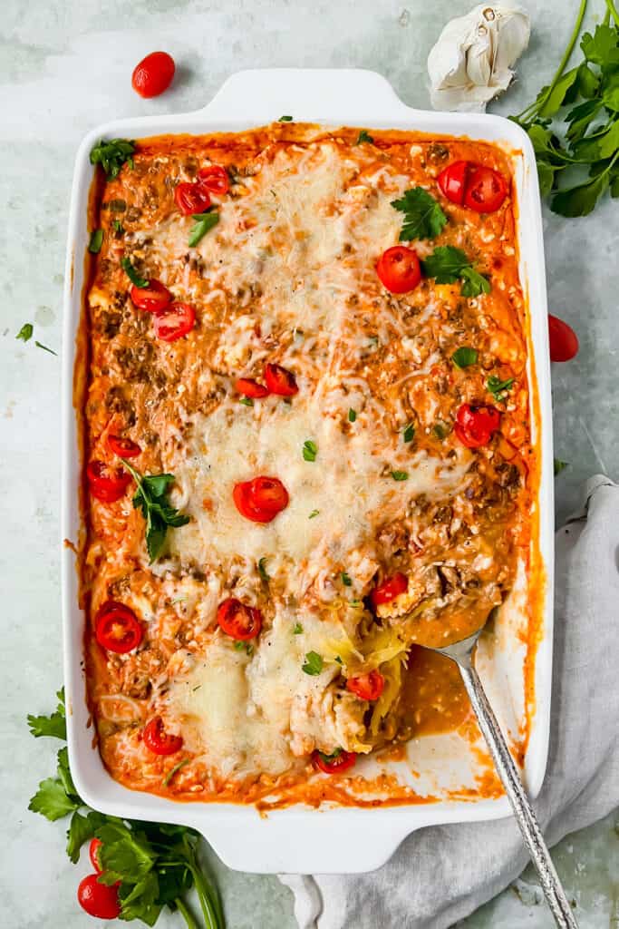 Baked spaghetti squash casserole in a baking dish with a serving spoon after being baked.