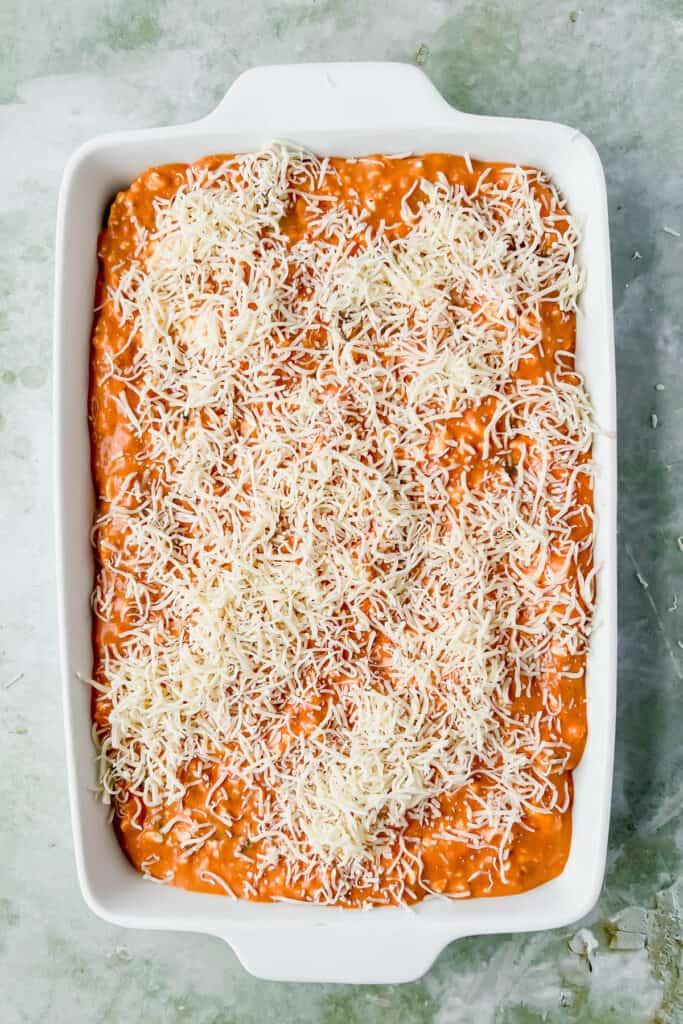 Spaghetti squash casserole topped with cheese in a baking dish before being baked.